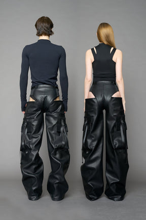 Model wearing Black vegan leather panty trousers featuring an integrated stretch panel for comfort, adjustable belt detail, and a relaxed high-waist silhouette.
