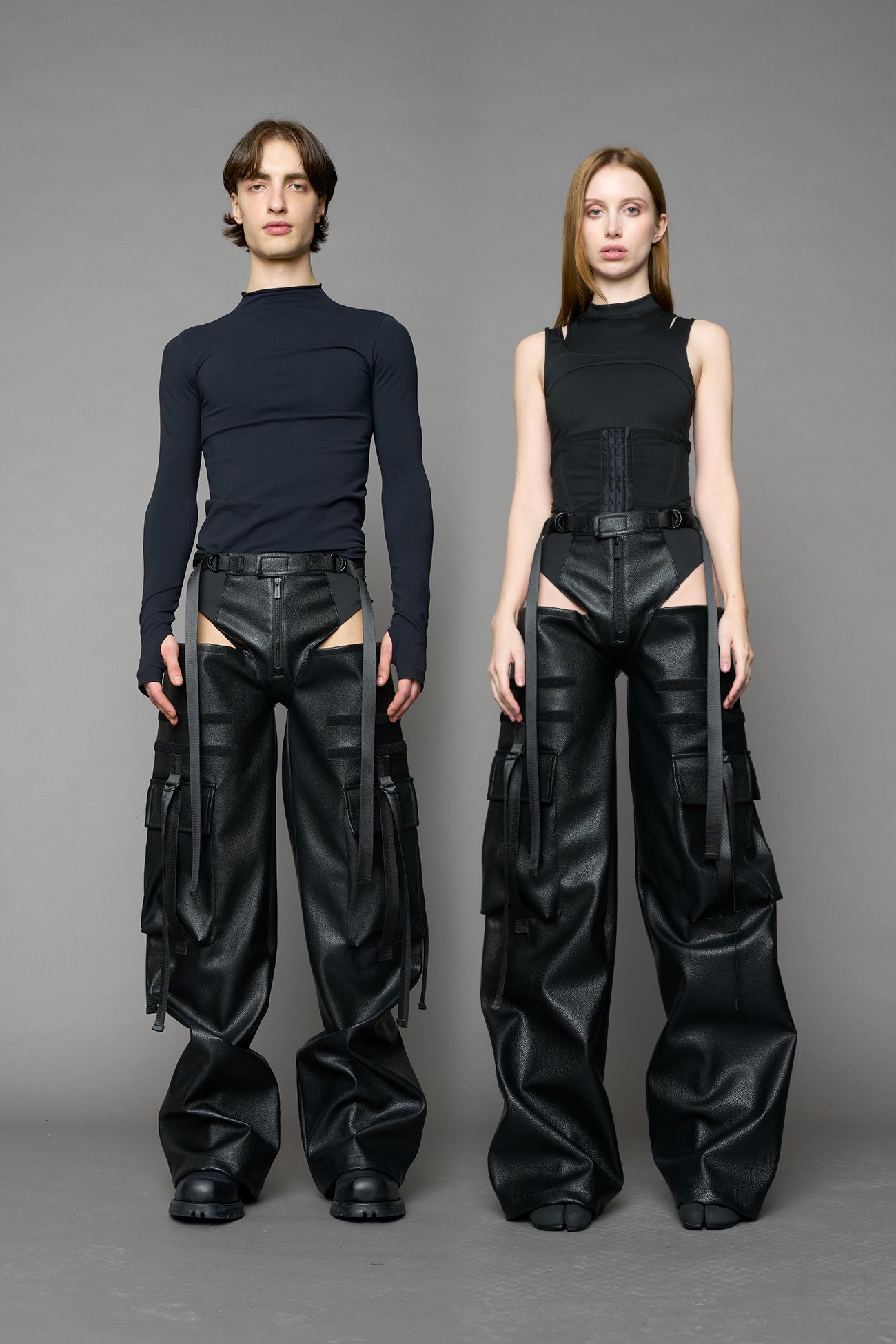 Model wearing Black vegan leather panty trousers featuring an integrated stretch panel for comfort, adjustable belt detail, and a relaxed high-waist silhouette.