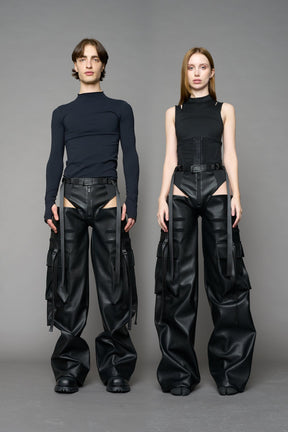 Model wearing Black vegan leather panty trousers featuring an integrated stretch panel for comfort, adjustable belt detail, and a relaxed high-waist silhouette.