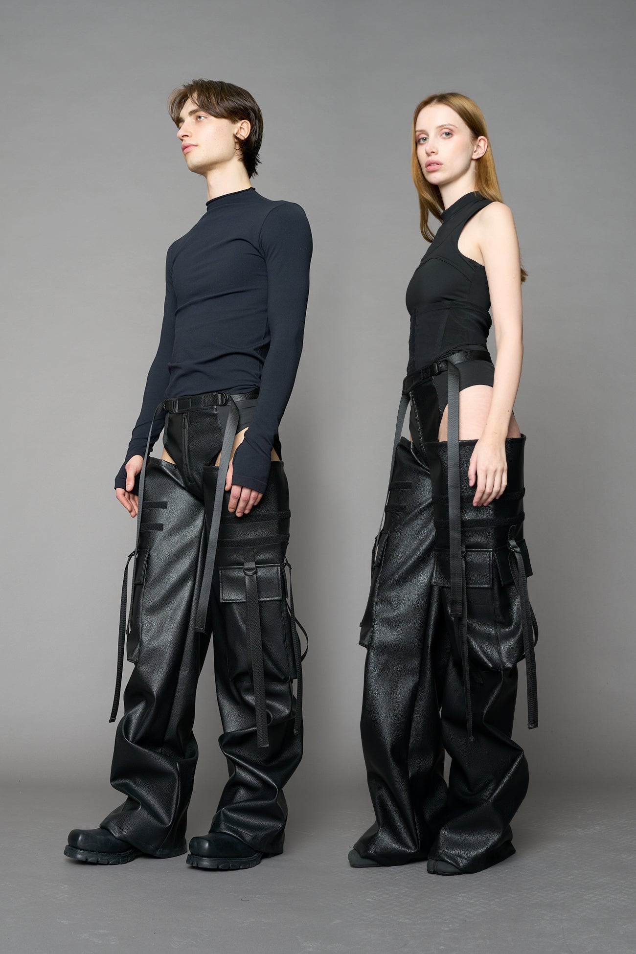 Model wearing Black vegan leather panty trousers featuring an integrated stretch panel for comfort, adjustable belt detail, and a relaxed high-waist silhouette.