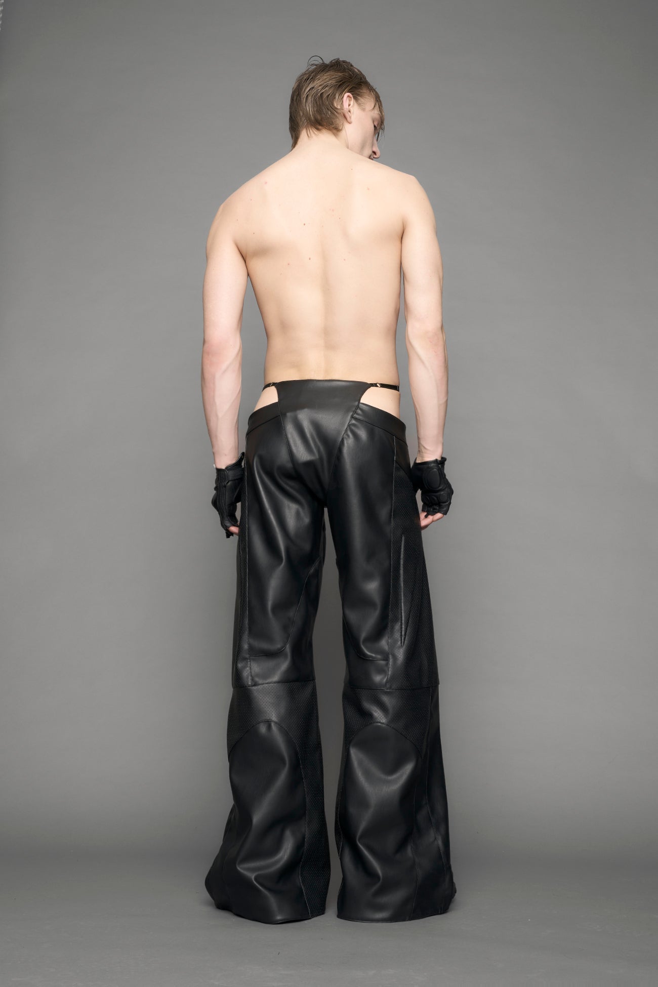 model wearing black vegan leather perforated thong pants