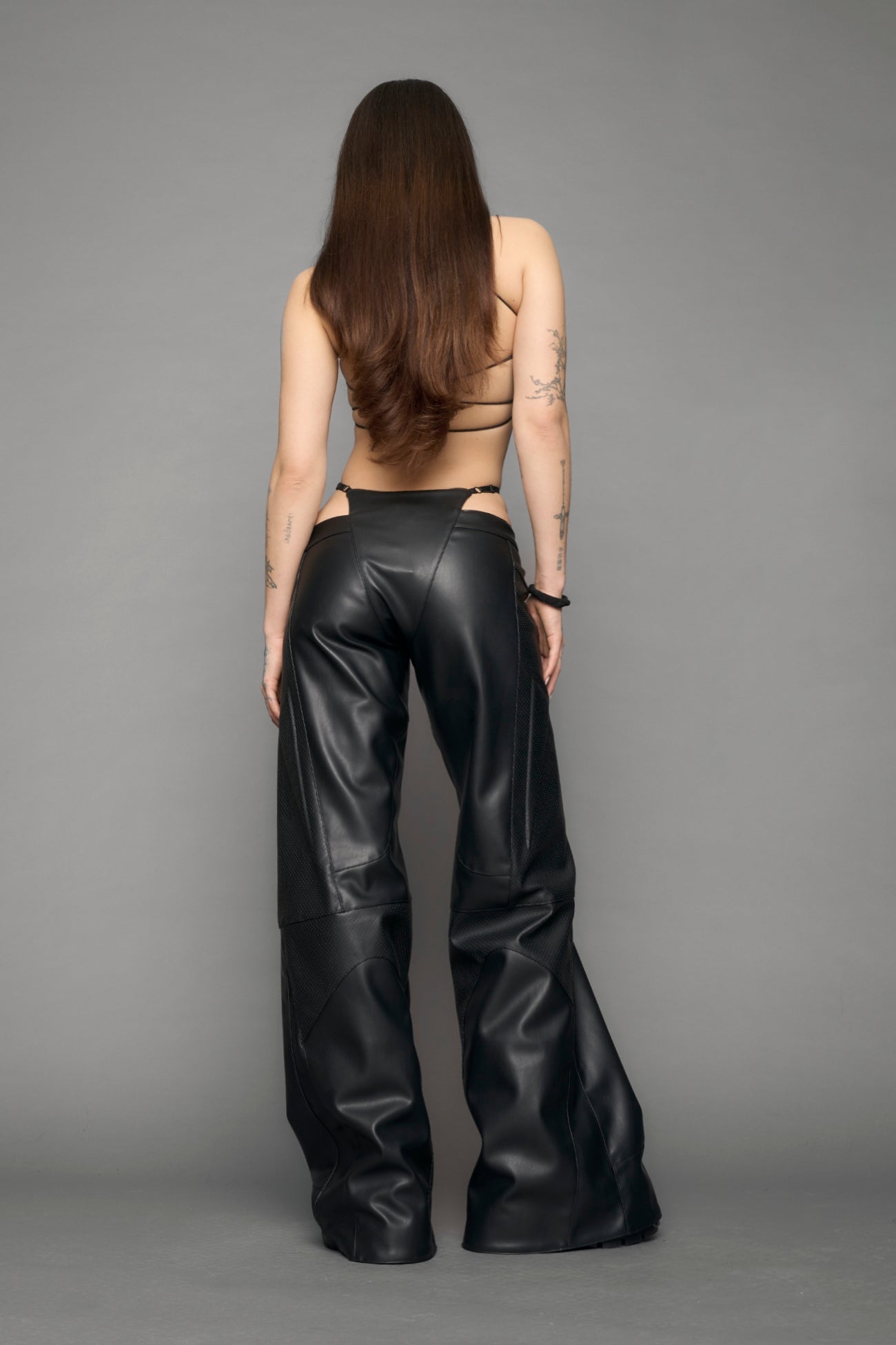 model wearing black vegan leather perforated thong pants