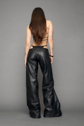 model wearing black vegan leather perforated thong pants
