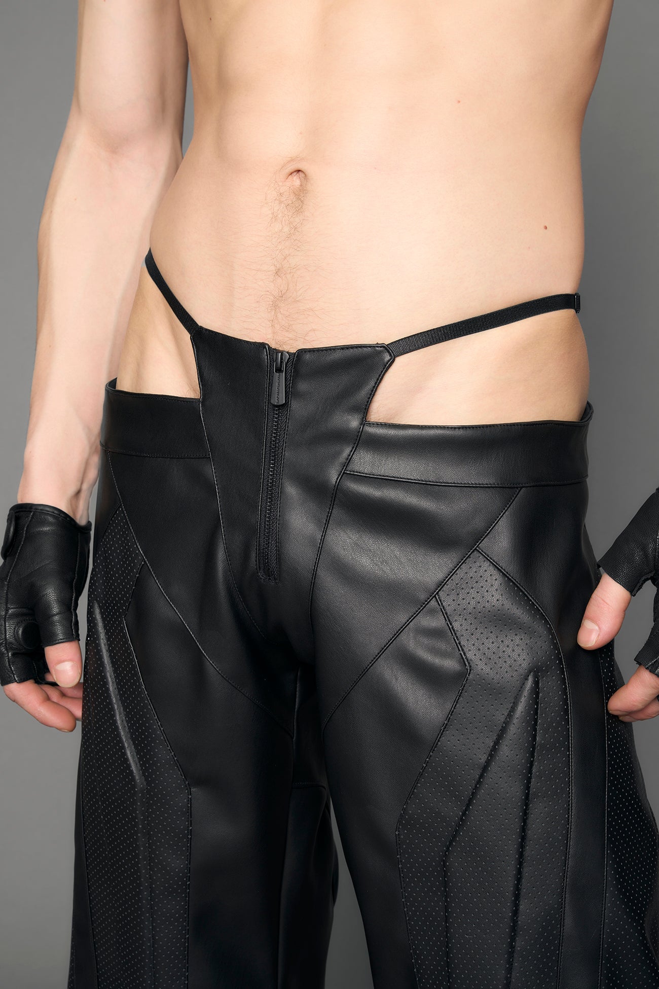model wearing black vegan leather perforated thong pants