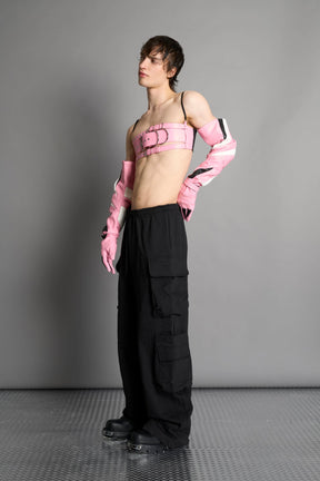 pink vegan leather belt top with three adjustable grommet straps, oversized metal buckles, and circular hardware – edgy bondage-inspired crop top for festival or clubwear.