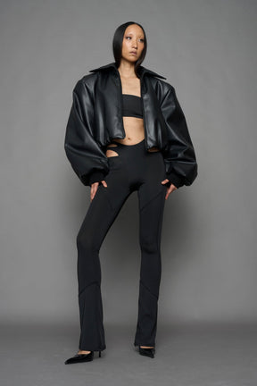 model wearing black puffy faux leather jacket with sharp collar and black pants 