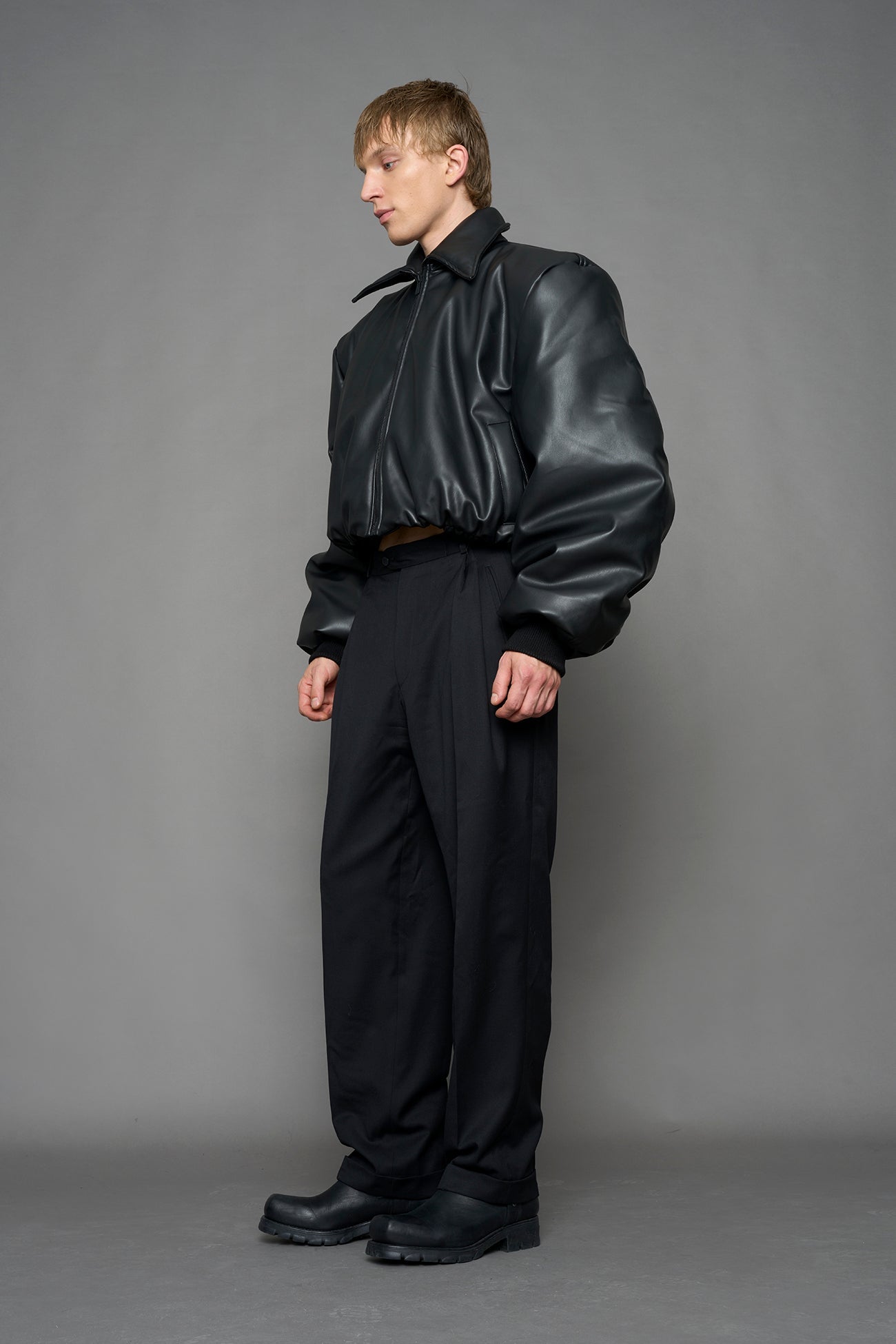 model wearing black puffy faux leather jacket with sharp collar and black pants 