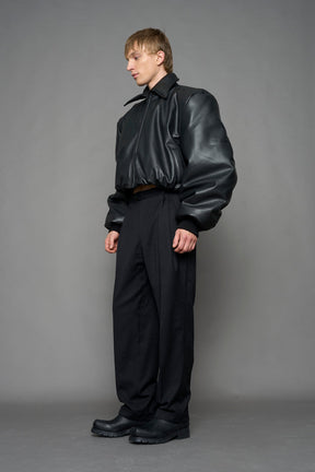 model wearing black puffy faux leather jacket with sharp collar and black pants 