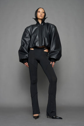 model wearing black puffy faux leather jacket with sharp collar and black pants 