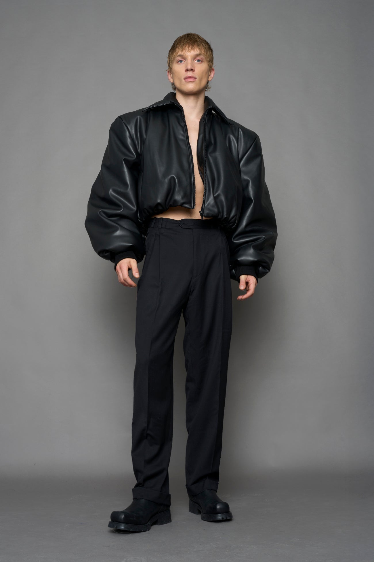 model wearing black puffy faux leather jacket with sharp collar and black pants 