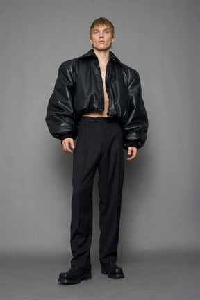 model wearing black puffy faux leather jacket with sharp collar and black pants 