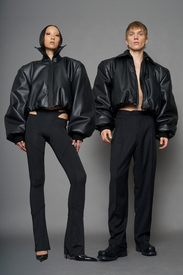 model wearing black puffy faux leather jacket with sharp collar and black pants 