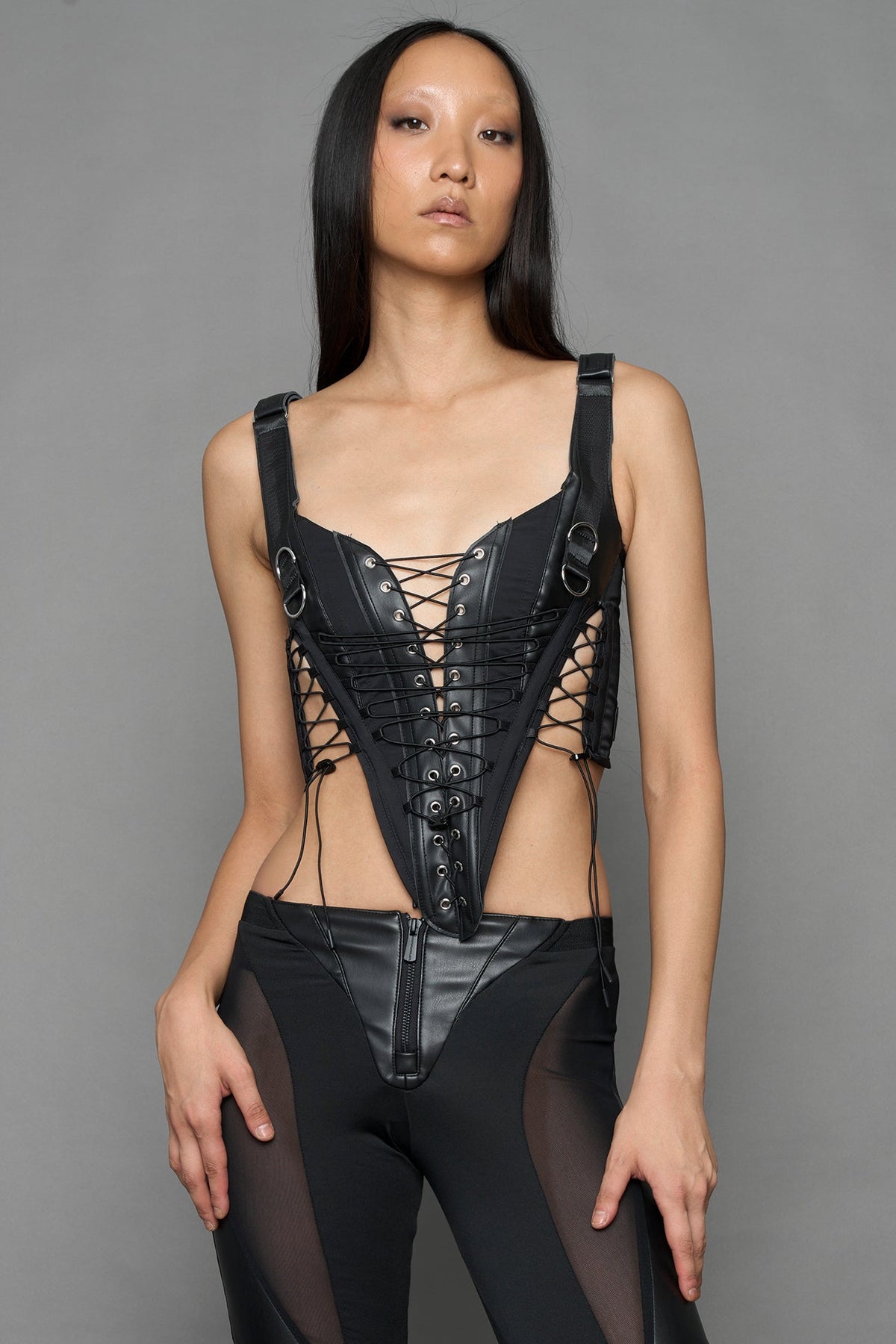 black faux leather lace up corset with sharp design details and buckle and ring details