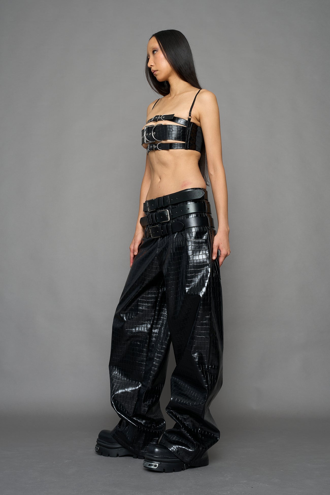 model wearing black vegan leather croc optic baggy pants with triple belt design detail