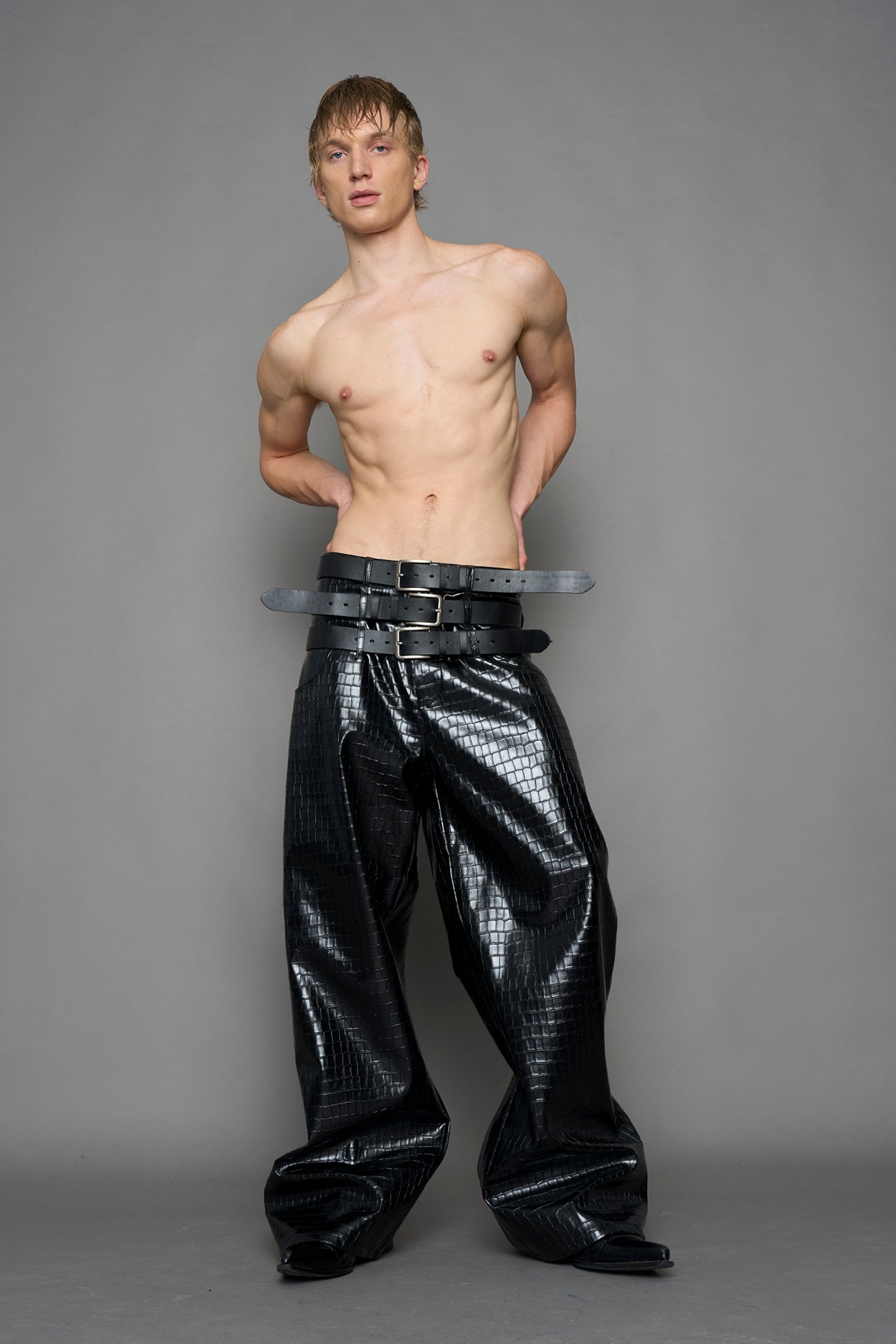 model wearing black vegan leather croc optic baggy pants with triple belt design detail