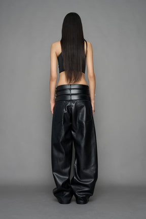 model wearing black vegan leather smooth optic baggy pants with triple belt design detail