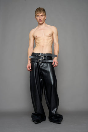 model wearing black vegan leather smooth optic baggy pants with triple belt design detail