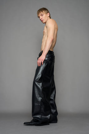 model wearing black vegan leather smooth optic baggy pants with triple belt design detail