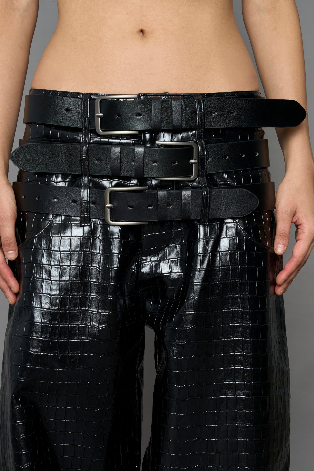 model wearing black vegan leather croc optic baggy pants with triple belt design detail