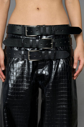 model wearing black vegan leather croc optic baggy pants with triple belt design detail