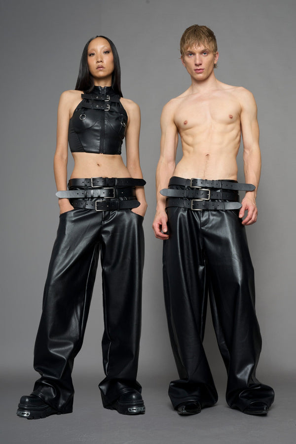 model wearing black vegan leather smooth optic baggy pants with triple belt design detail - black