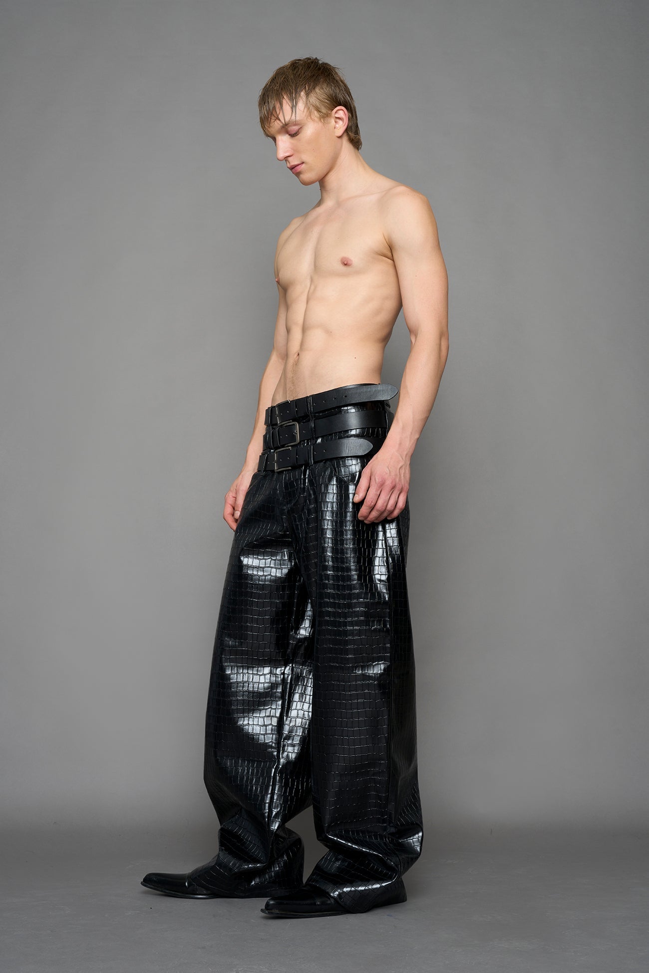 model wearing black vegan leather croc optic baggy pants with triple belt design detail