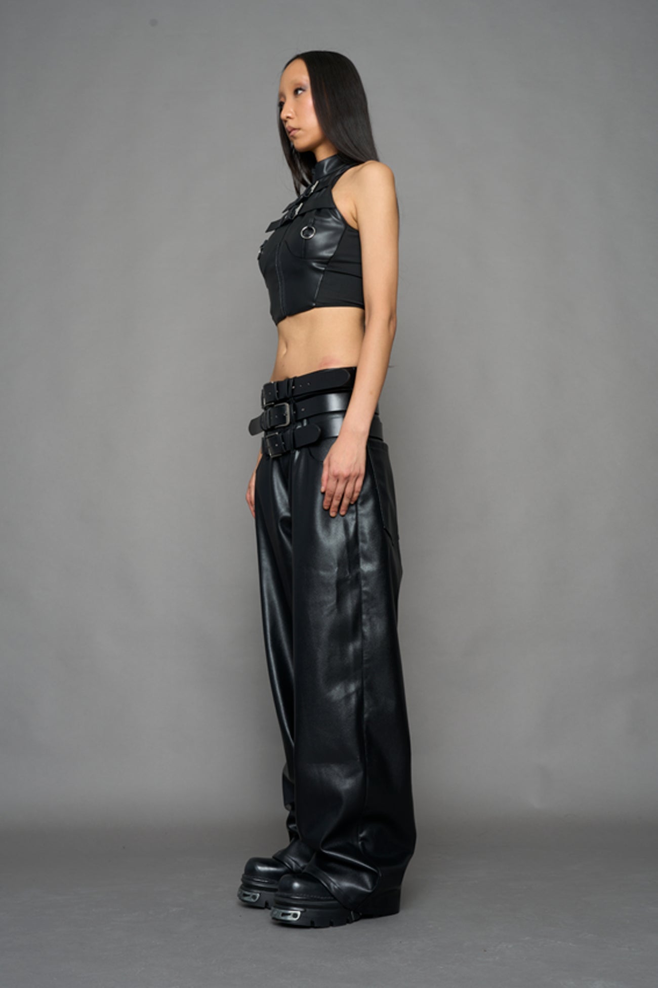 model wearing black vegan leather smooth optic baggy pants with triple belt design detail