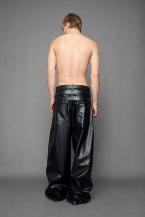 model wearing black vegan leather smooth optic baggy pants with triple belt design detail