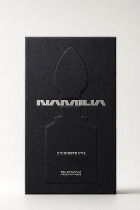 A tall black rectangular box for Namila Concrete Eau de Parfum, featuring a large embossed perfume bottle silhouette and silver lettering, photographed against a light gray background.