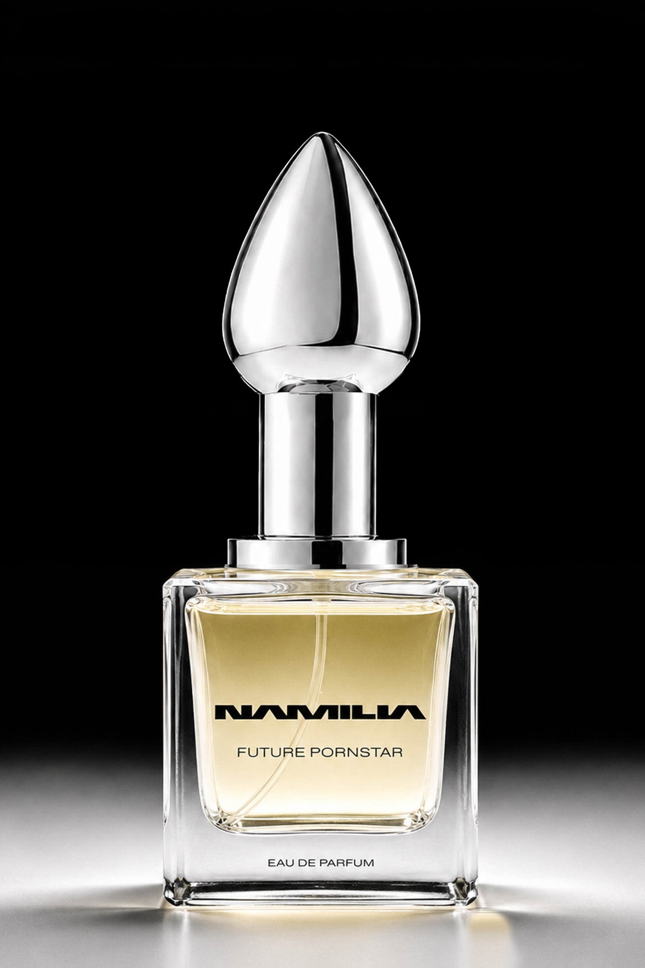 A square glass perfume bottle with pale yellow liquid, a reflective silver neck, and a teardrop-shaped silver cap, centered on a black background. The bottle is labeled 'NAMILA FUTURE Pornstar EAU DE PARFUM'.