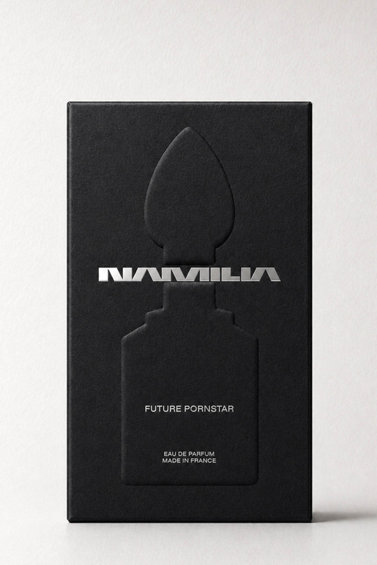 A tall black rectangular box with a large embossed perfume bottle silhouette and the word 'NAMILA' in metallic silver across the front, plus smaller text reading 'FUTURE PORNSTAR' and 'EAU DE PARFUM MADE IN FRANCE,' photographed on a light neutral background.