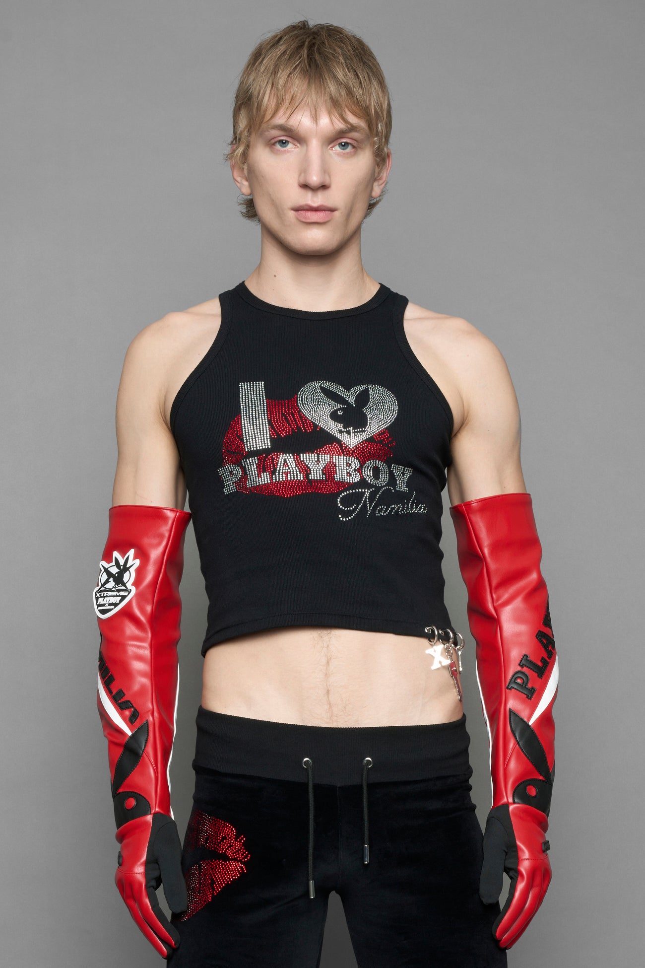 model wearing red and white Playboy x NAMILIA vegan leather gloves and mesh pants with white panels.