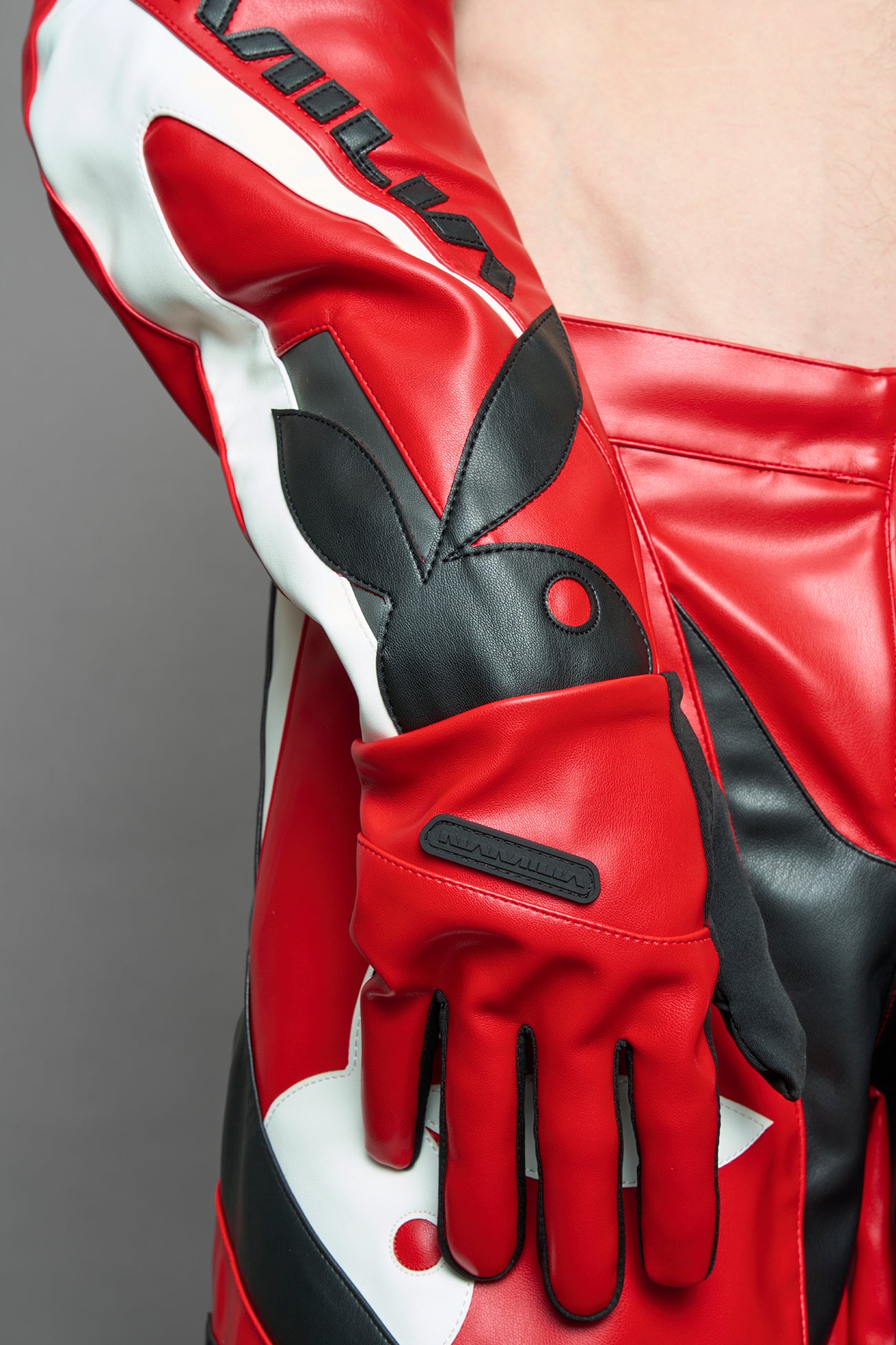 model wearing red and white Playboy x NAMILIA vegan leather gloves and mesh pants with white panels.