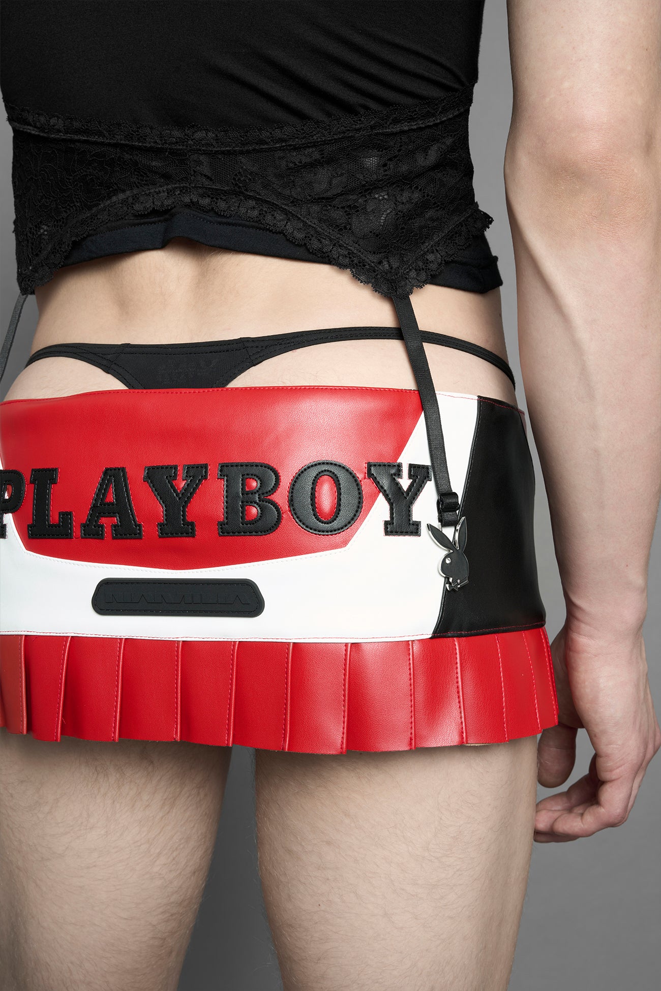 model wearing vegan leather NAMILIA x playboy pleated mini skirt with velcro closure